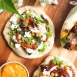 Three flatbreads piled with honey harissa chicken, salad and feta.