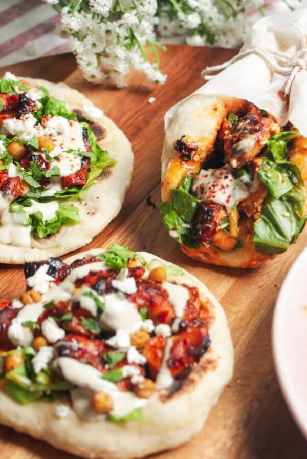 Three flatbreads piled with honey harissa chicken, salad and feta.