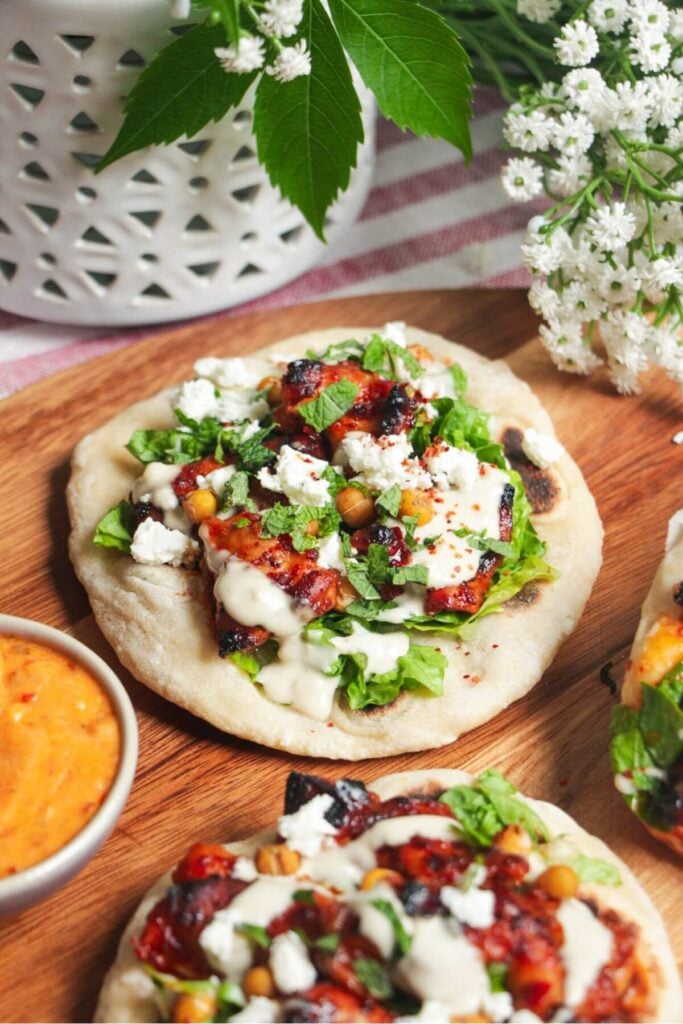 A flatbread piled with honey harissa chicken, salad and feta.