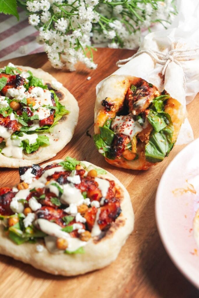 Three flatbreads piled with honey harissa chicken, salad and feta.
