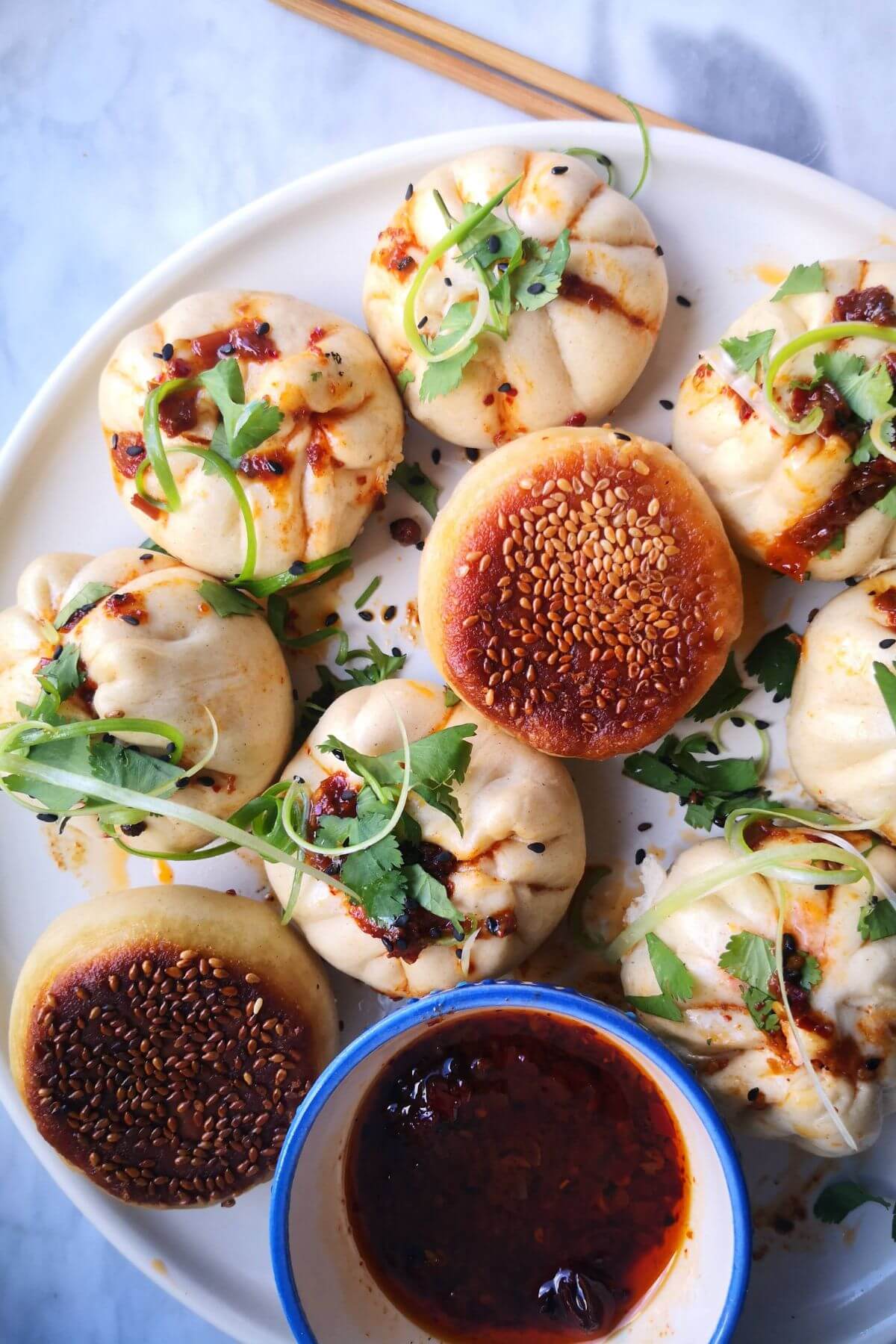 Korean steamed buns on a plate with cilantro and scallions.