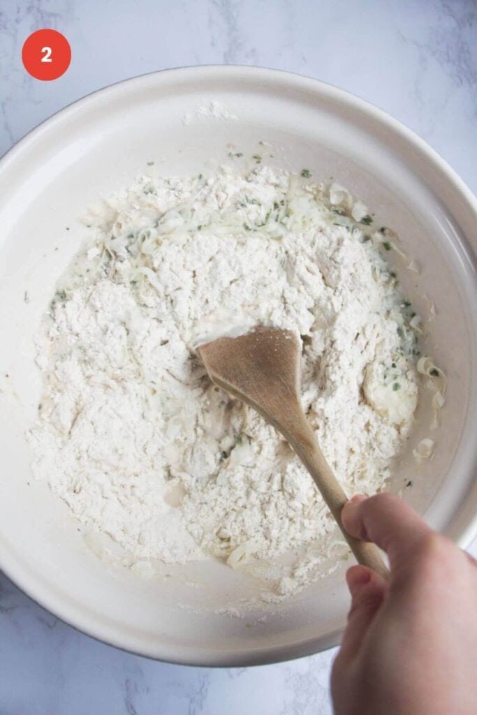 Mixing ingredients for rosemary parmesan bread in bowl.