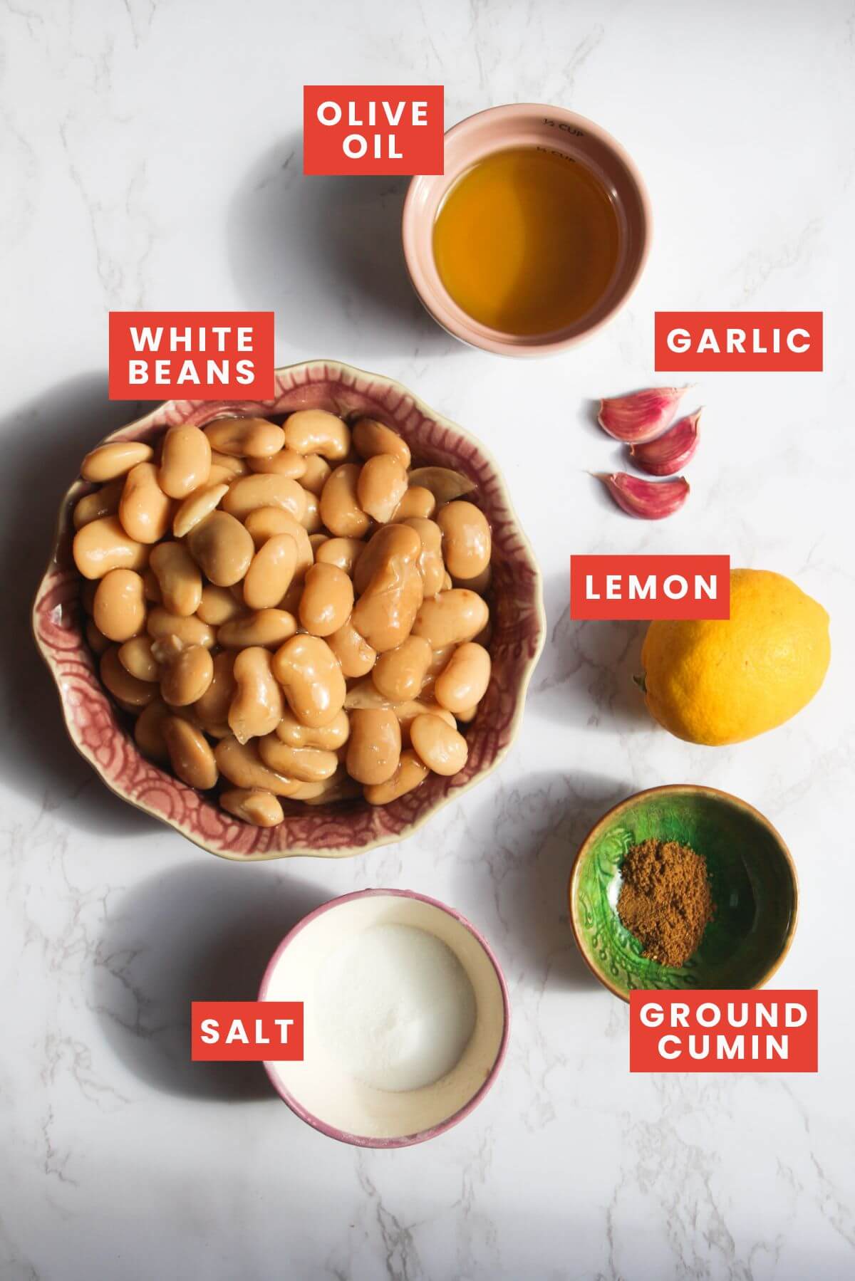 Ingredients for white bean dip laid out on a white marble background.
