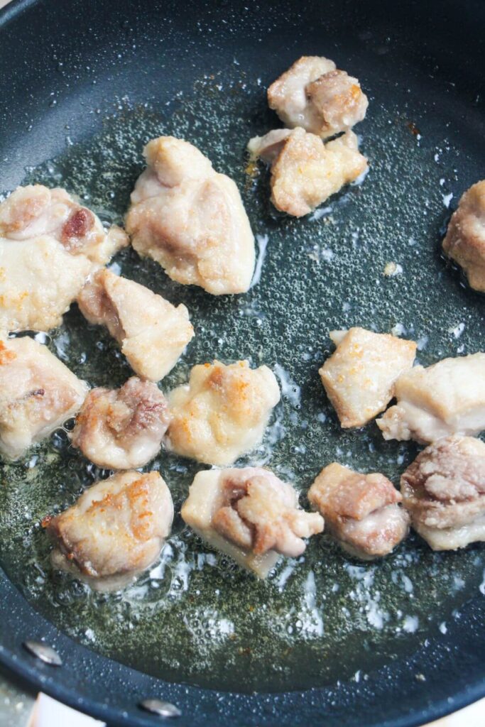 Pan frying pieces of chicken in a small frying pan.