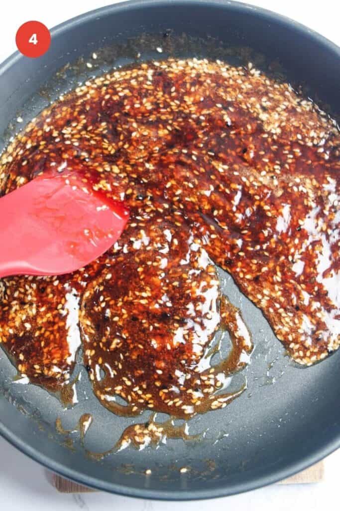 Spatula stirring honey sesame sauce in pan.