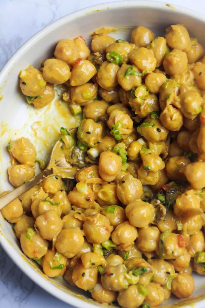 Coronation chickpeas mixed in a small white bowl.
