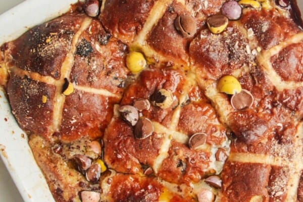 Baked hot cross bun bread and butter pudding in a white baking dish.
