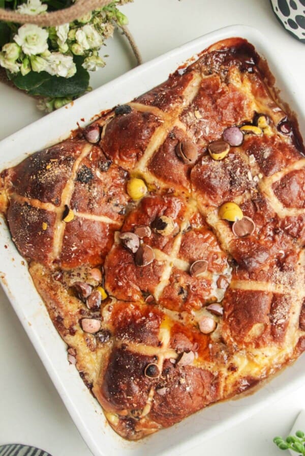 Baked hot cross bun bread and butter pudding in a white baking dish.