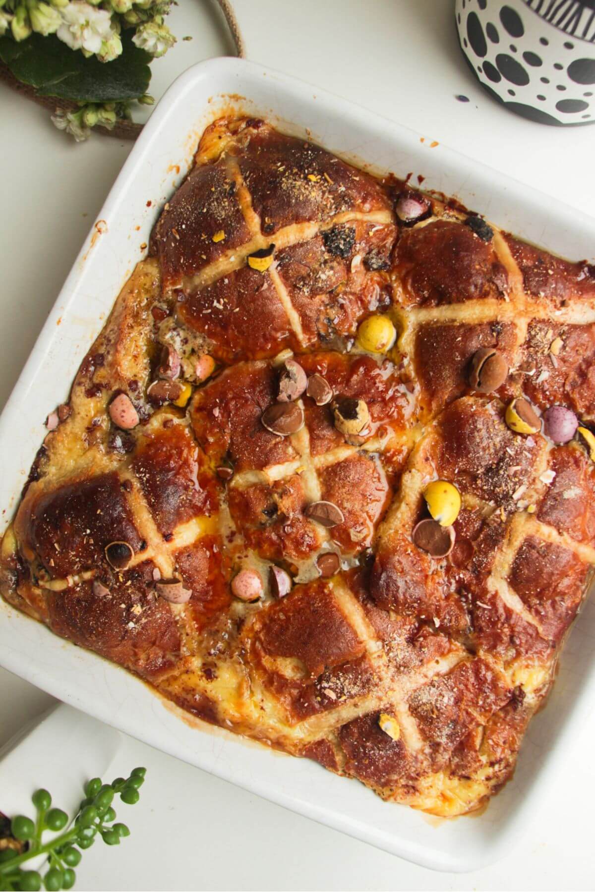 Baked hot cross bun bread and butter pudding in a white baking dish.
