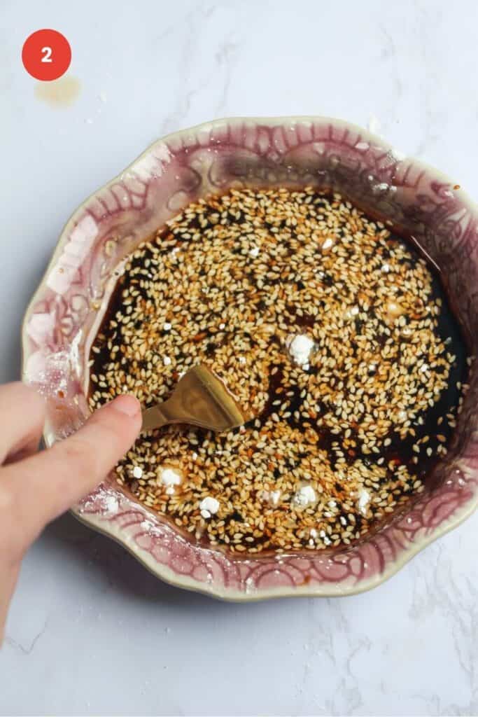 Fork mixing honey sesame sauce in bowl.