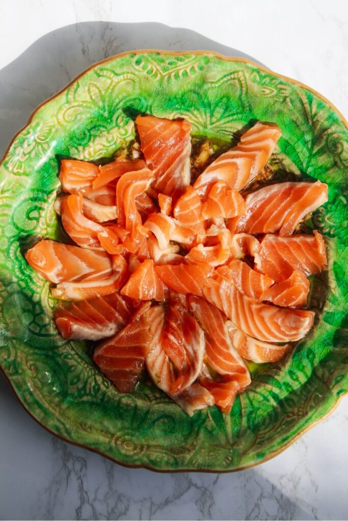 Thinly sliced salmon on a small green plate.
