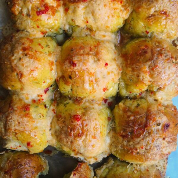 12 wild garlic hot cross buns on a lined baking tray.