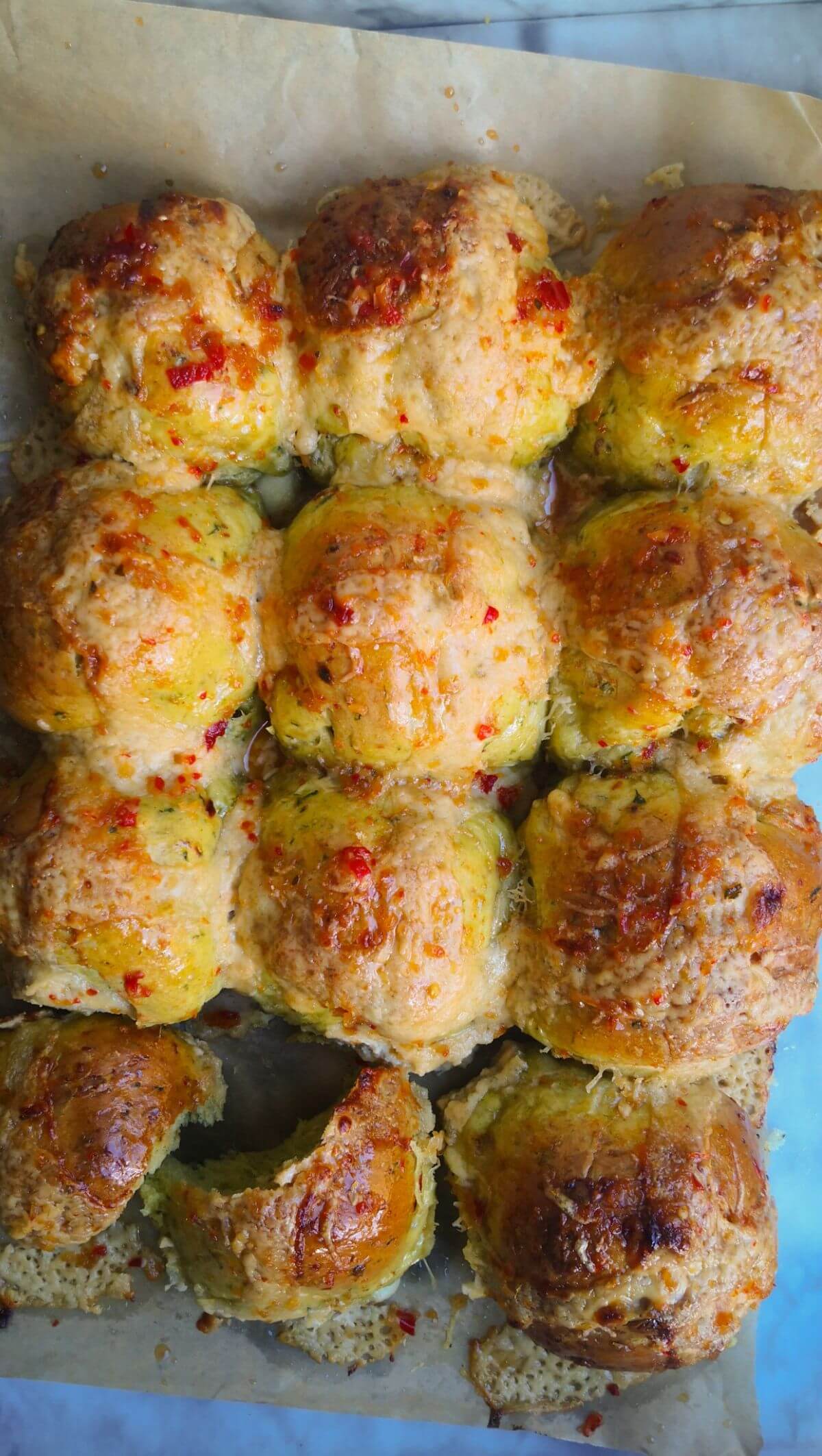 12 wild garlic hot cross buns on a lined baking tray.