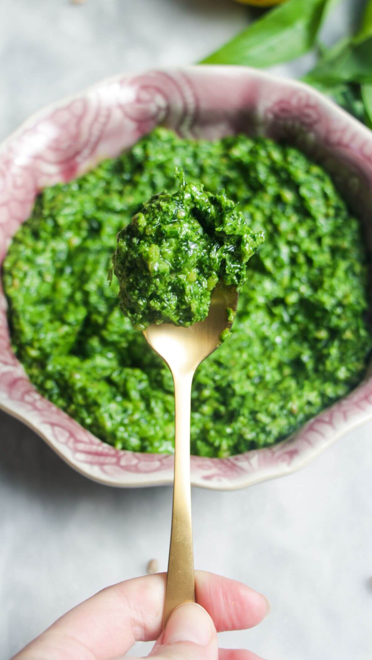 Close up of wild garlic pesto on a small gold spoon.