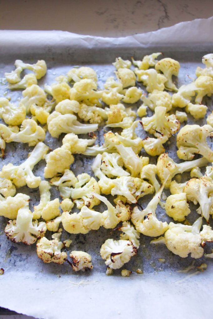 Cauliflower florets on a baking paper lined oven tray.