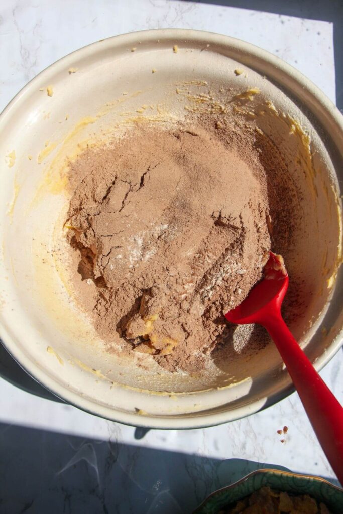 Sifted flour and cocoa powder in a large mixing bowl with creamed butter and sugar.