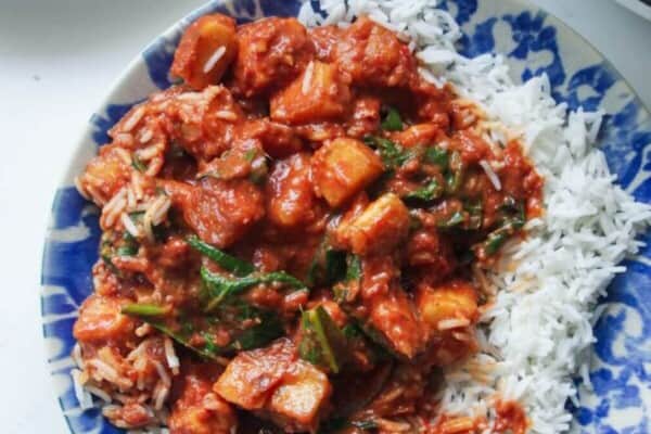 Creamy halloumi curry with spinach on rice on a small plate.