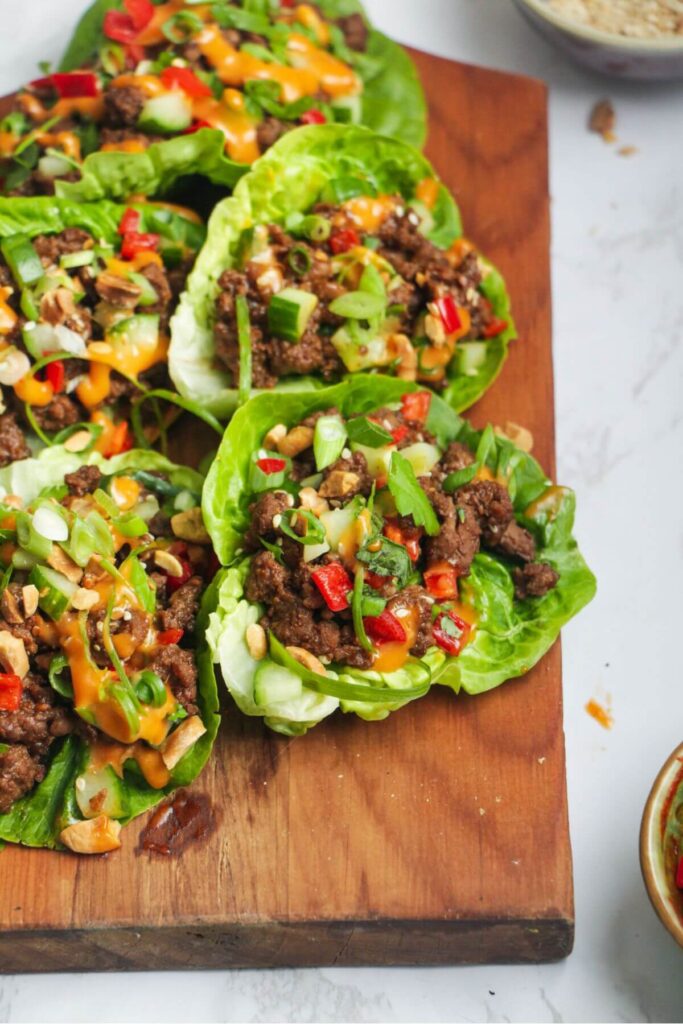Korean beef lettuce wraps on a wooden board, with lettuce on the side.