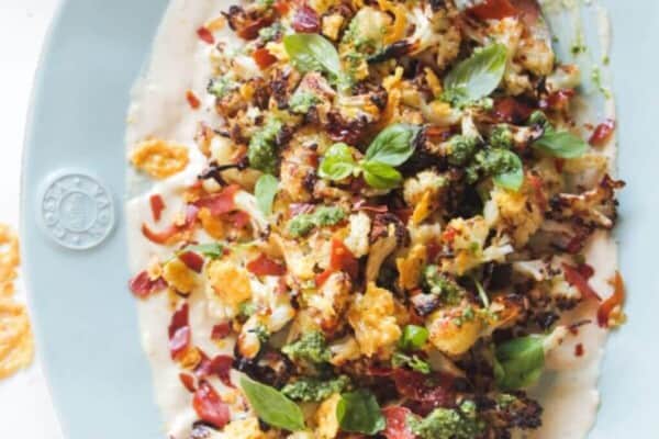 Parmesan roasted cauliflower salad on an oven blue plate with crispy parmesan and prosciutto.