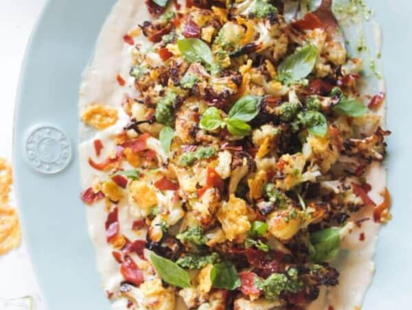 Parmesan roasted cauliflower salad on an oven blue plate with crispy parmesan and prosciutto.