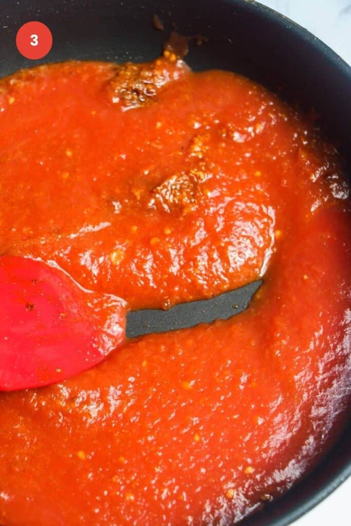 Tomato passata added to spices in a pan.