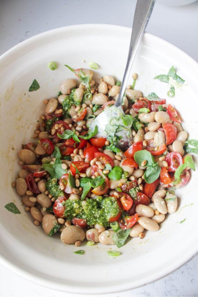 White beans, tomatoes, basil and pine nuts in a large mixing bowl.