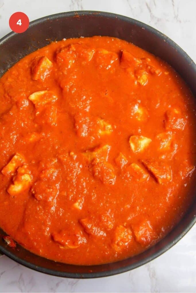 Halloumi added to coconut tomato sauce in a pan.