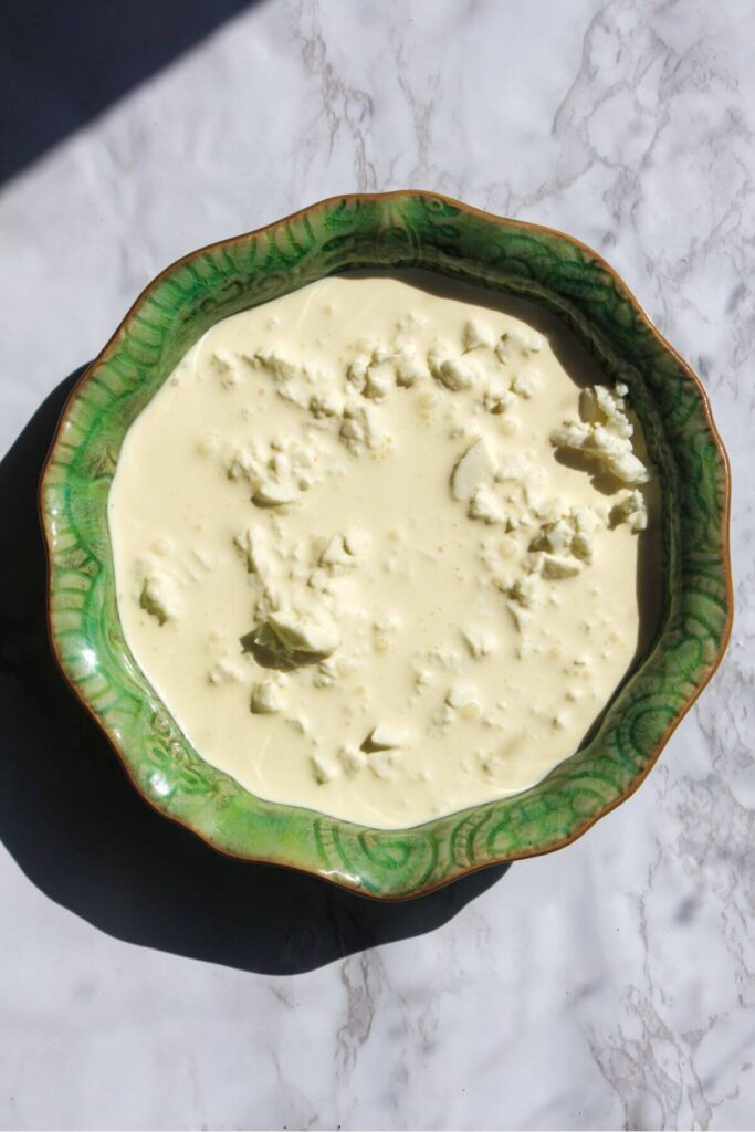 Cream poured over chopped mozzarella in a small green bowl.