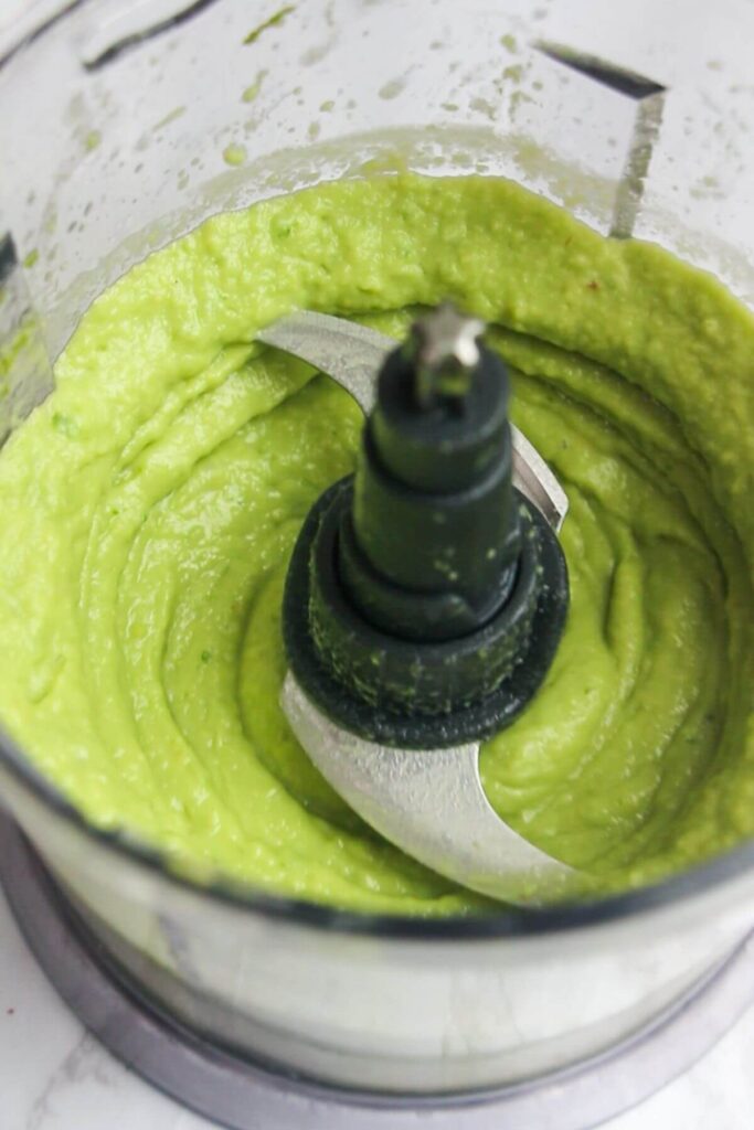 Creamy green whipped avocado in a small food chopper.