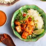Crispy salmon bites on top of rice, with lime and cilantro.