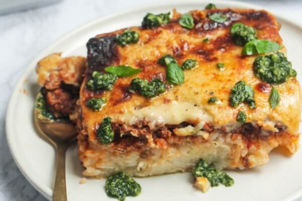 Bolognese Rice Bake on a small white plate, with another plate of the bake in the background.