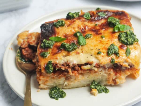 Bolognese Rice Bake on a small white plate, with another plate of the bake in the background.