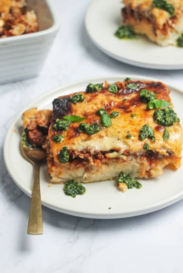 Bolognese Rice Bake on a small white plate, with another plate of the bake in the background.