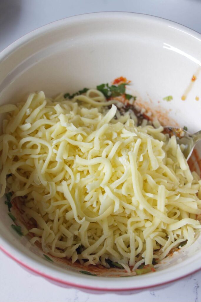Grated mozzarella in a large white bowl.