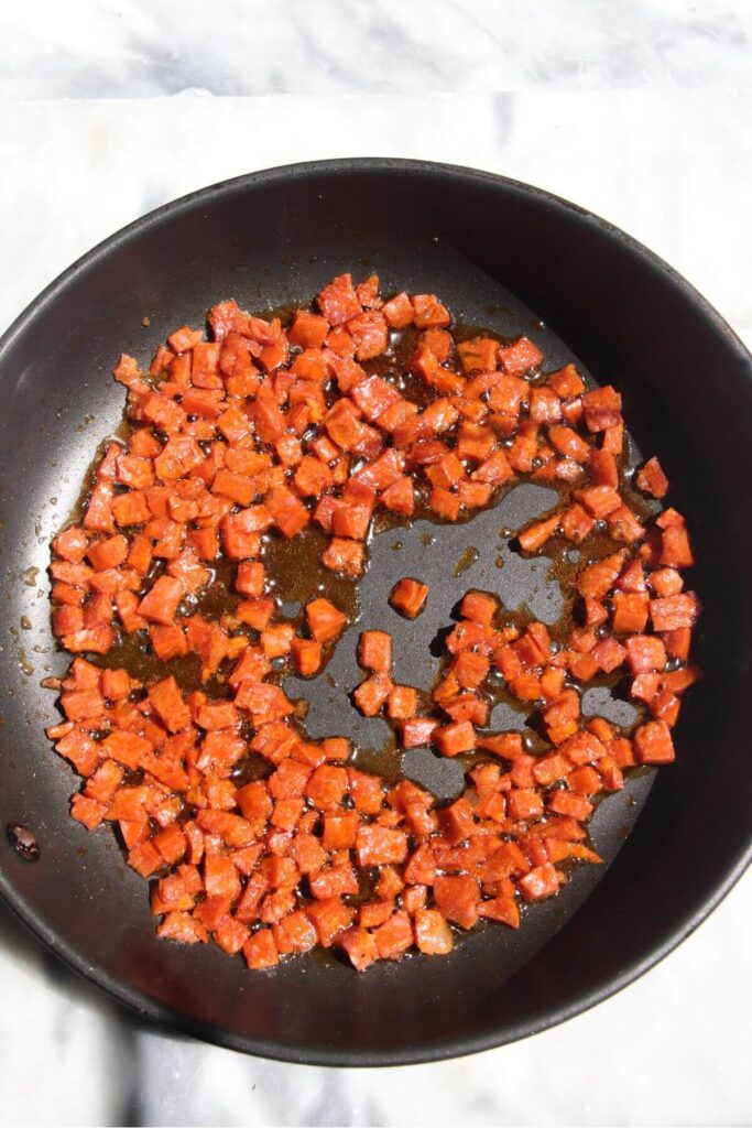 Diced chorizo in a small black pan.