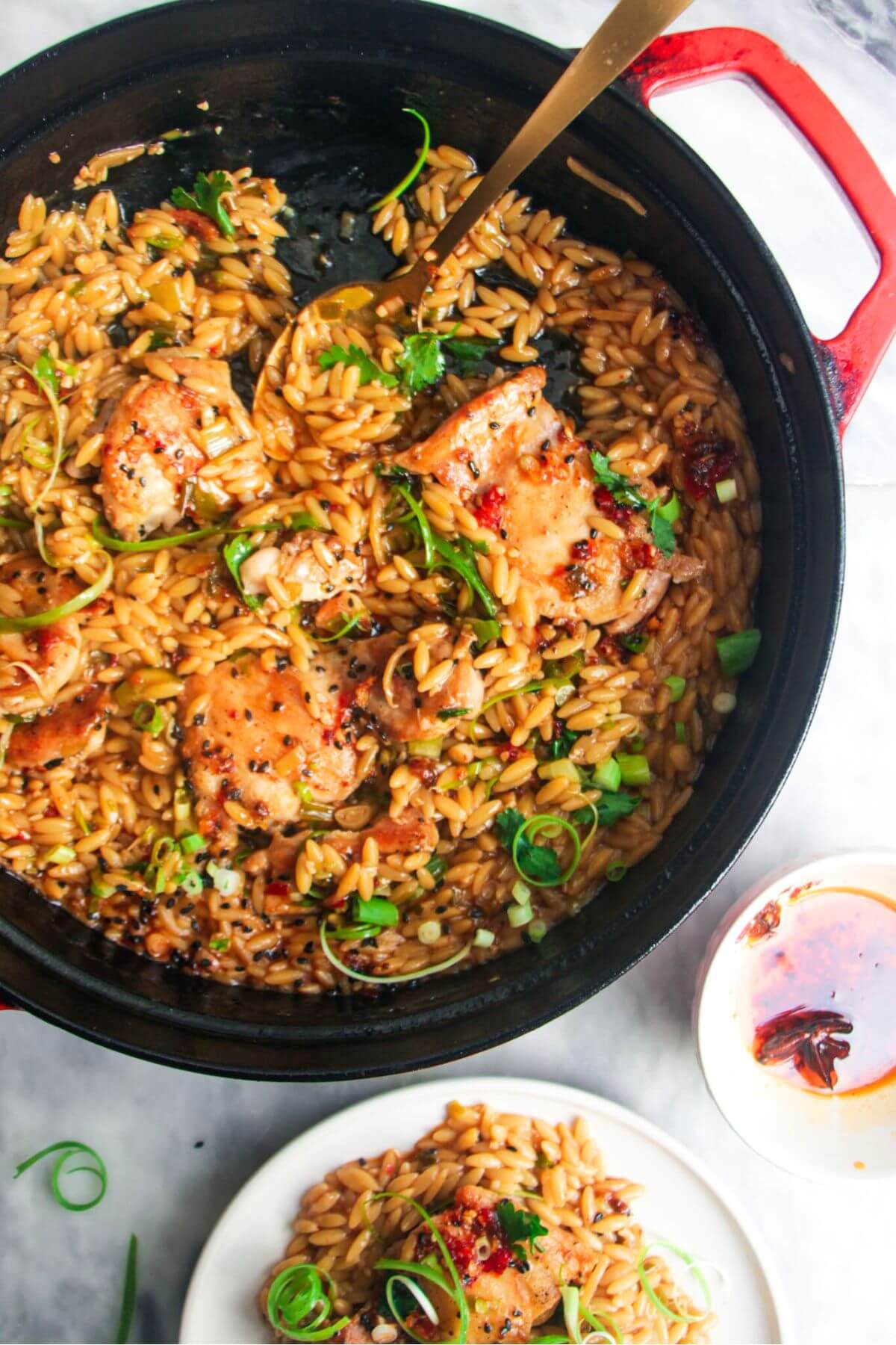 Ginger chicken orzo in a large black skillet, with more chicken orzo in a small plate on the side.
