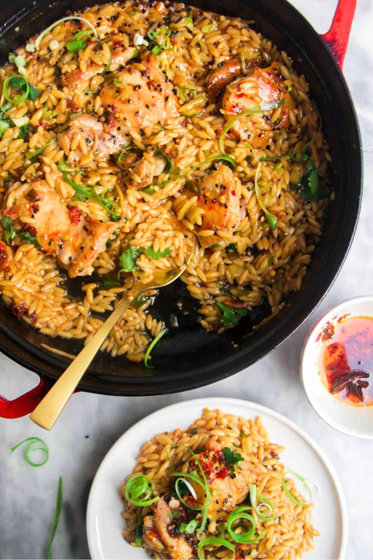 Ginger chicken orzo in a large black skillet, with more chicken orzo in a small plate on the side.