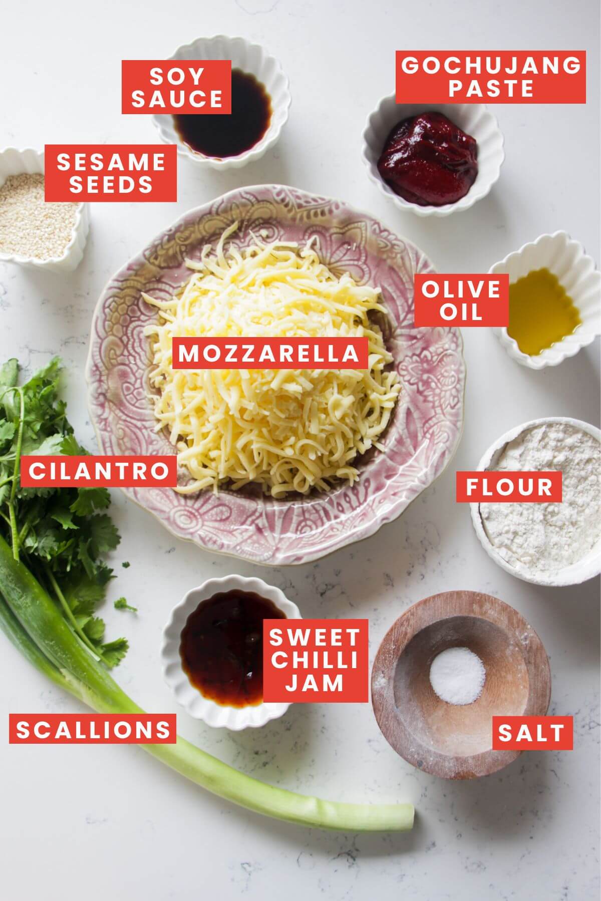 Ingredients for cheesy gochujang pizza pockets laid out on a white marble background and labelled.