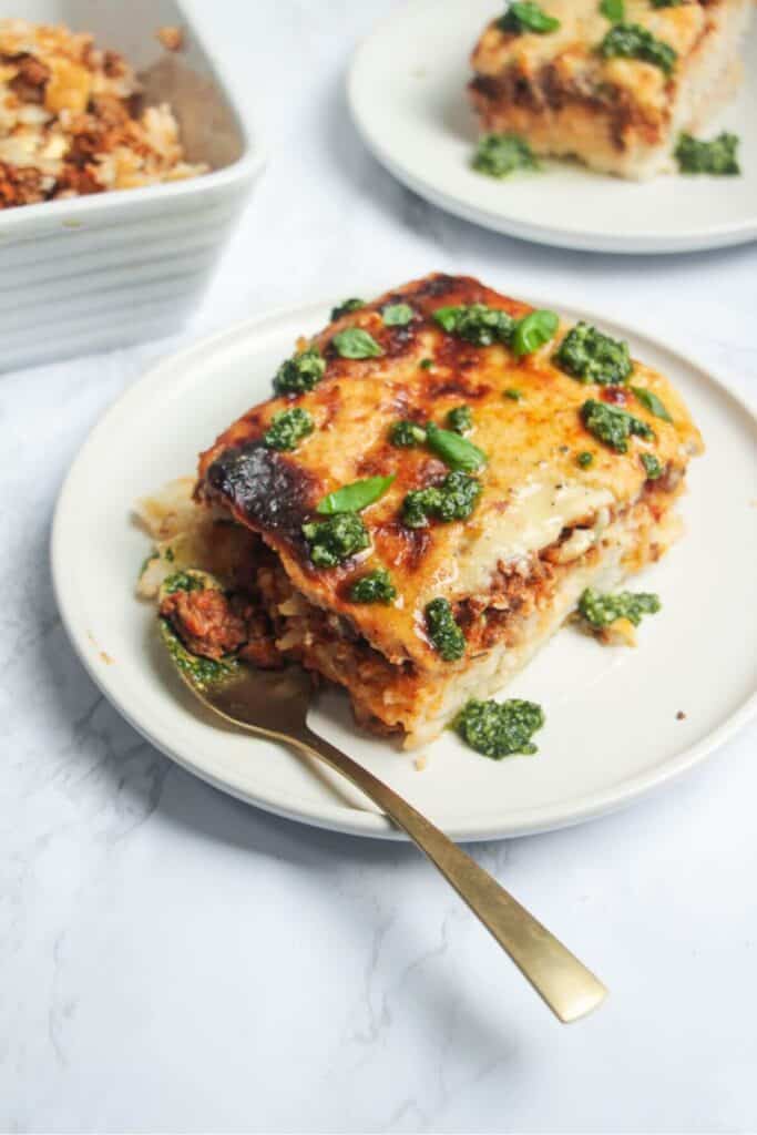 Bolognese Rice Bake on a small white plate, with another plate of the bake in the background.