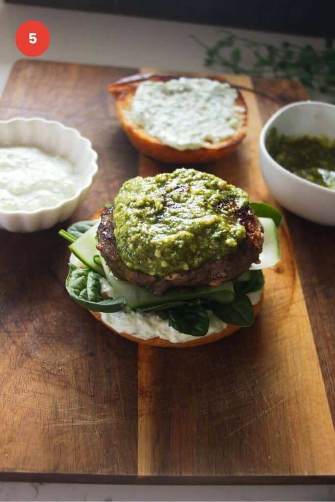 Lamb burger patty on bun with sauce and salad.