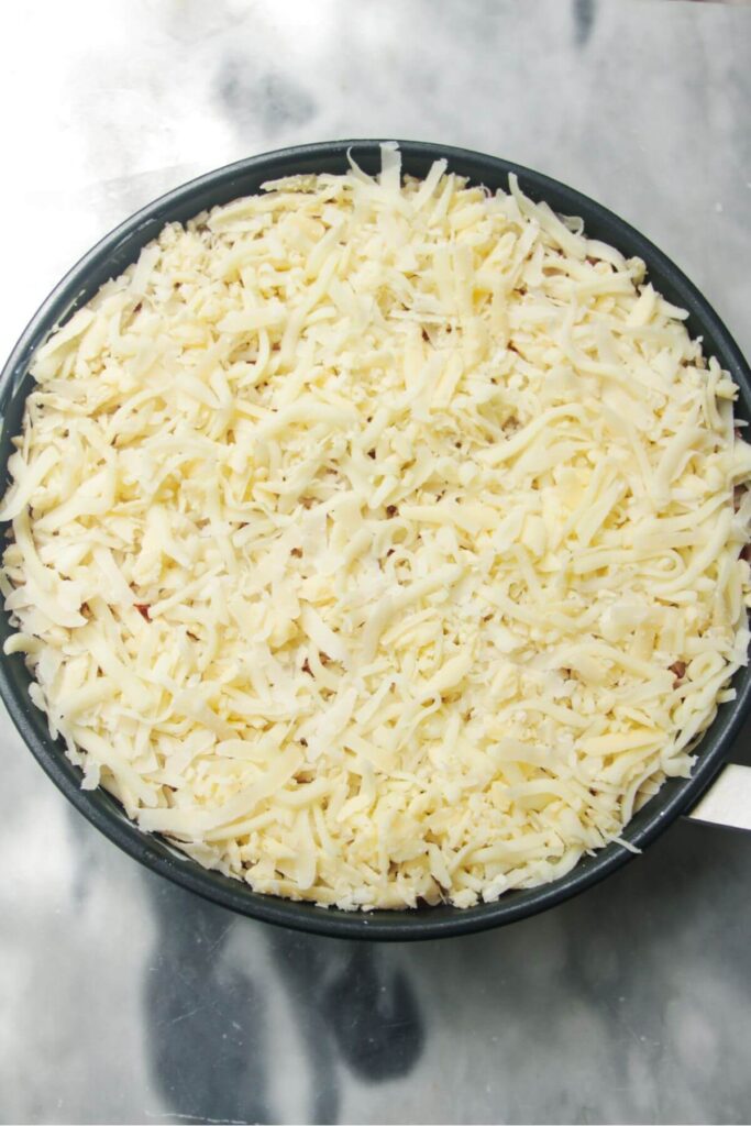 Grated cheese in a small black pan.