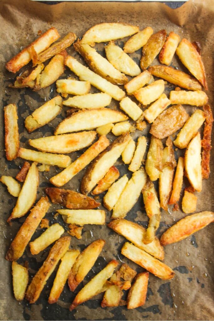 Cooked fries on a baking paper lined tray.