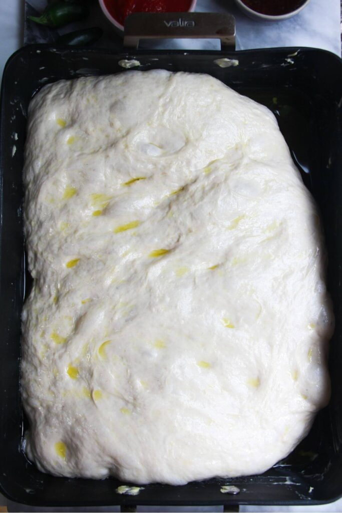 Focaccia dough risen in an oven tray.