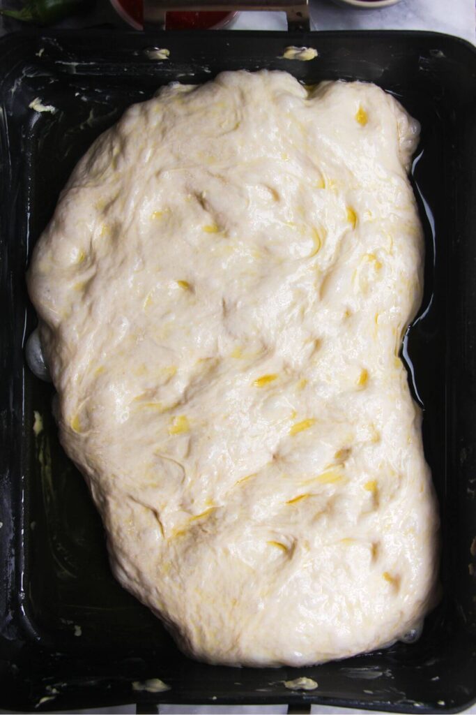 Focaccia dough in a large oven tray.
