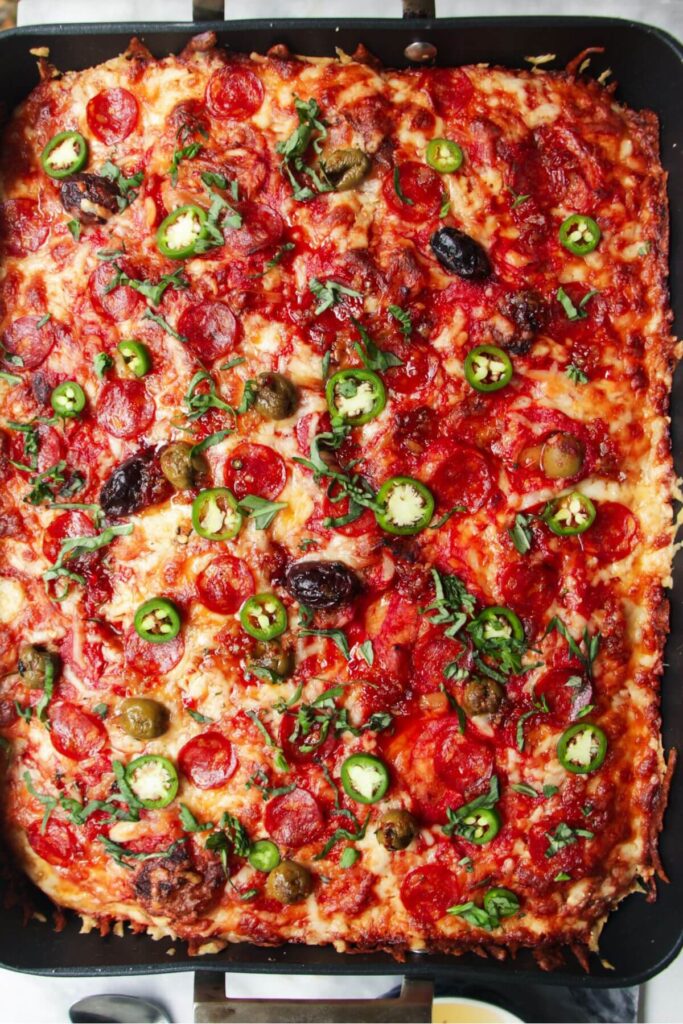 Jalapenos and sweet chilli drizzled on top of baked focaccia pizza in a large oven tray.