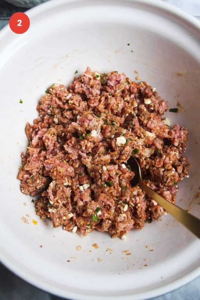 Ground lamb mixed with spices in a mixing bowl.