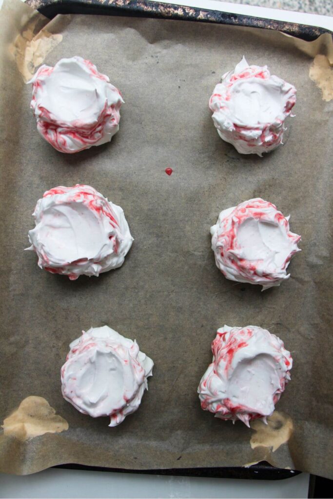 6 berry ripple pavlovas on a baking paper lined tray, pre-baking.