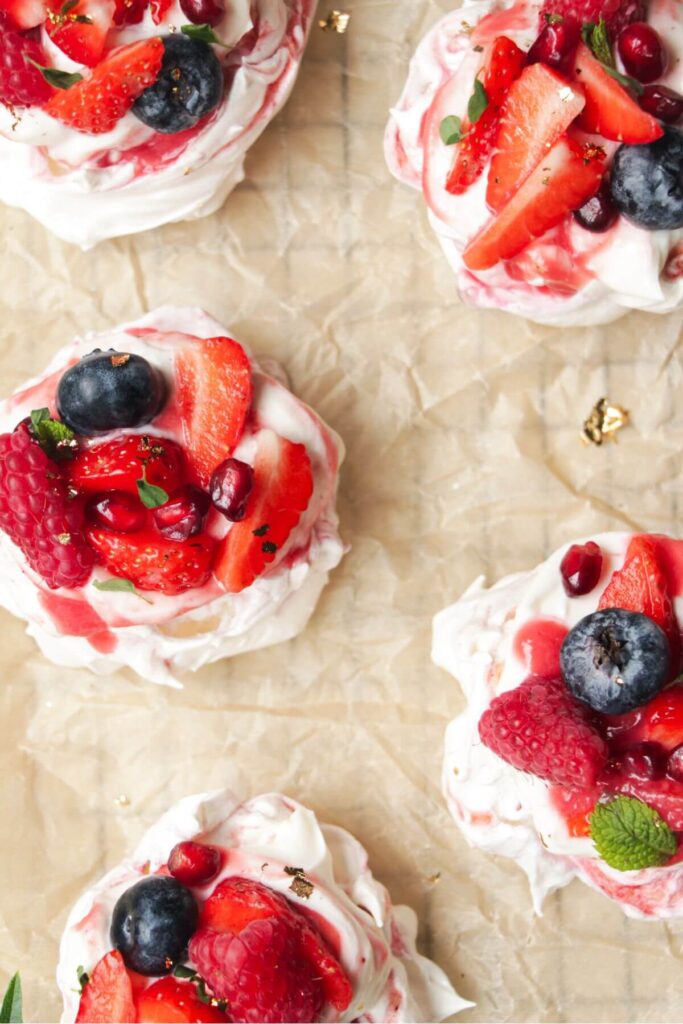 Close up of mini berry ripple cheesecake pavlovas topped with berries.