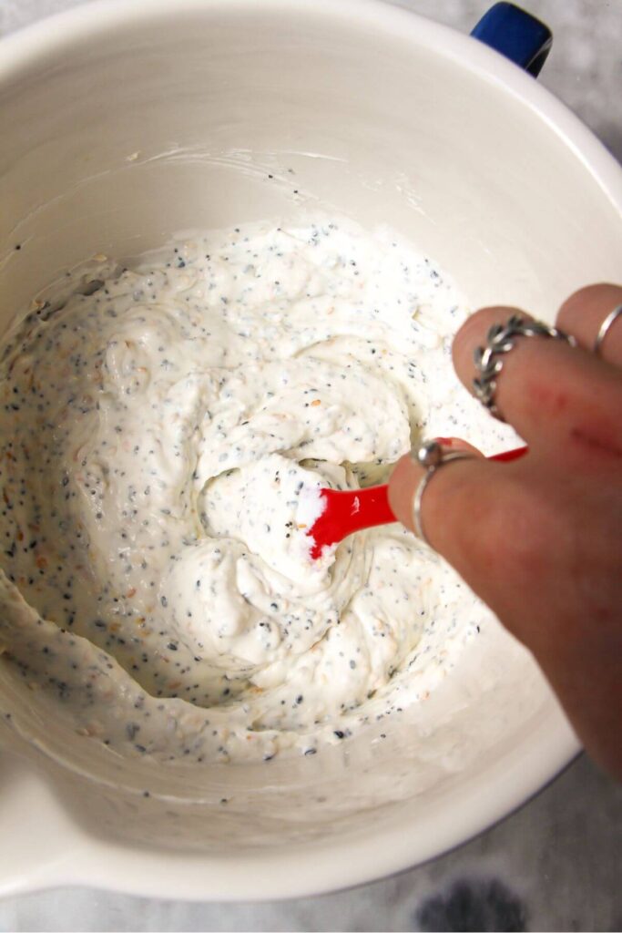 Mixing Greek yogurt, cream cheese and everything bagel seasoning in a mixing bowl.