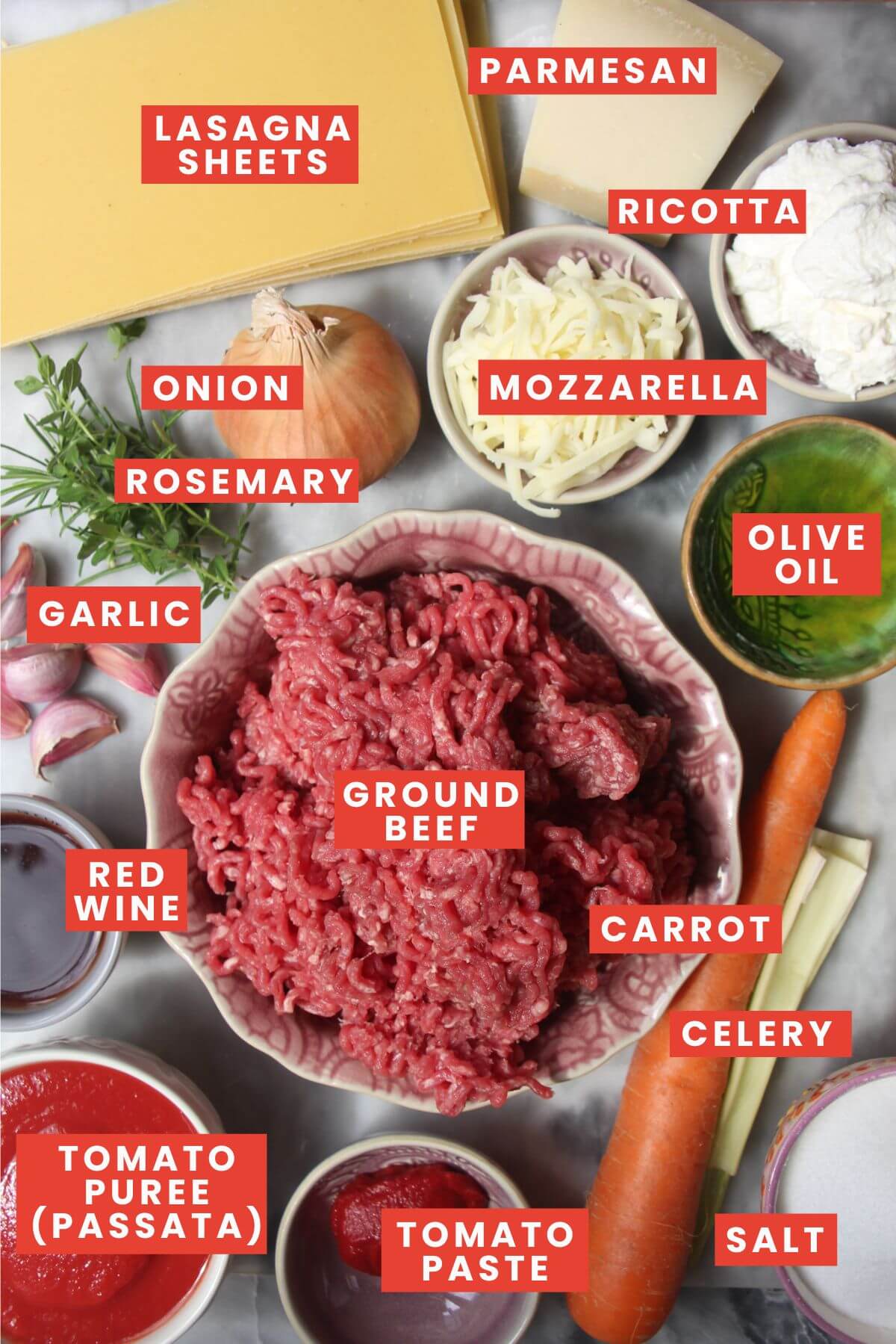 Ingredients for one pot lasagna laid out on a grey marble background and labelled.